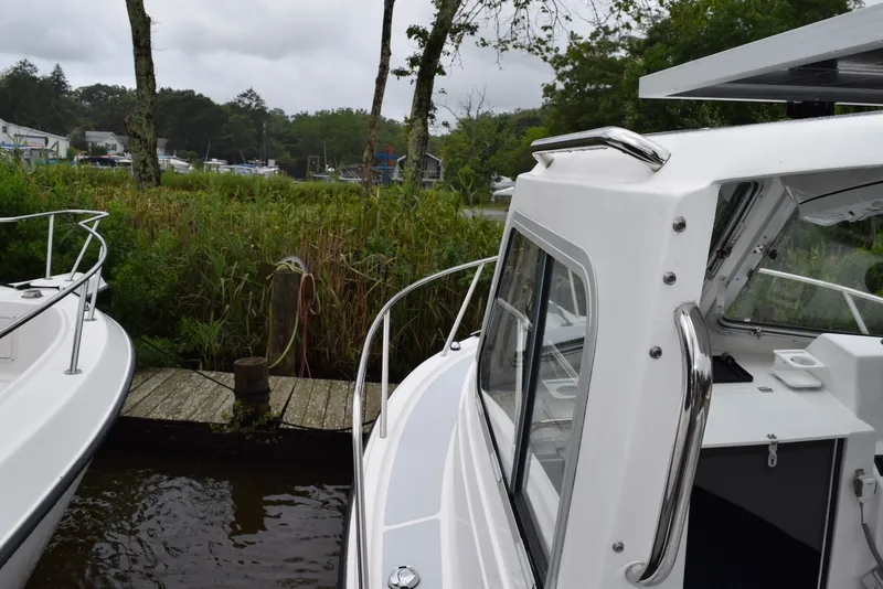 Slide: The Image of 2023 NorthCoast 215 HT boat docked near lush greenery on a cloudy day. - 22