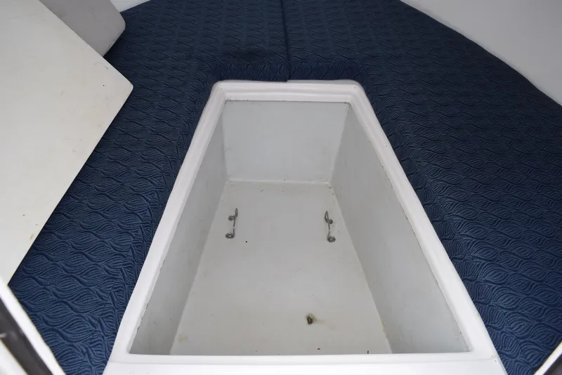 Slide: The Image of 2023 NorthCoast 215 HT boat interior storage compartment with blue cushioned seating. - 19