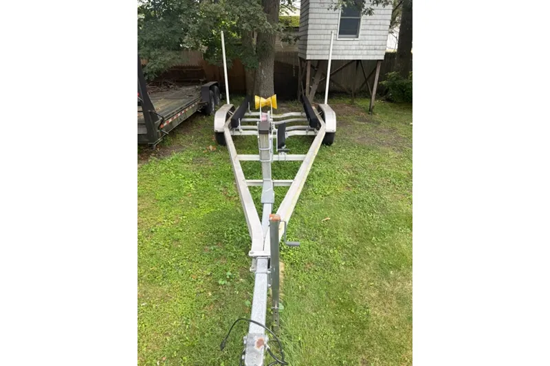 Slide: The Image of Trailer for 2023 NorthCoast 215 HT boat on grassy yard, near treehouse. - 25