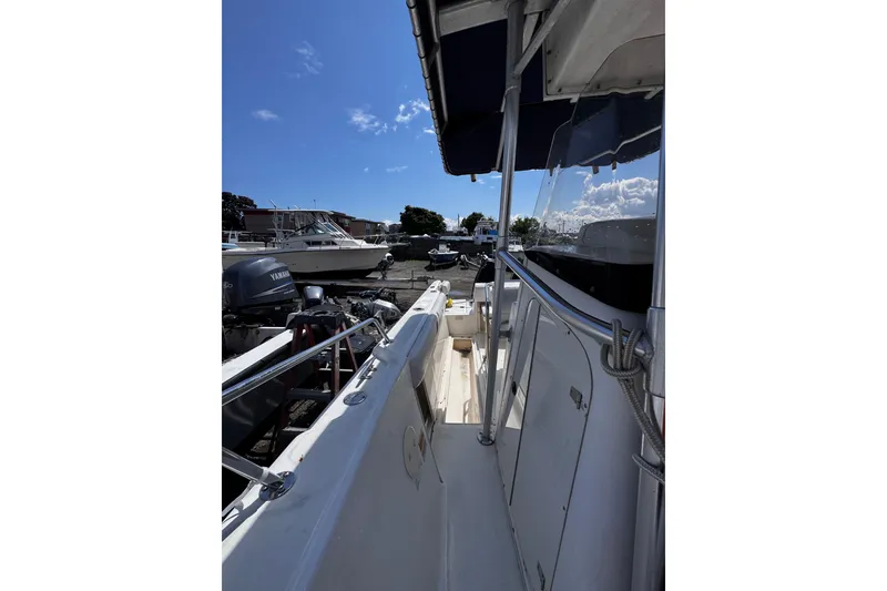 Slide: The Image of 2001 Boston Whaler 23 Outrage boat docked, featuring Yamaha outboard motor under clear blue sky. - 11