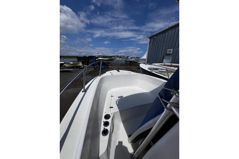 Slide: The Image of 2001 Boston Whaler 23 Outrage boat docked, showcasing spacious deck and clear blue sky. - 10