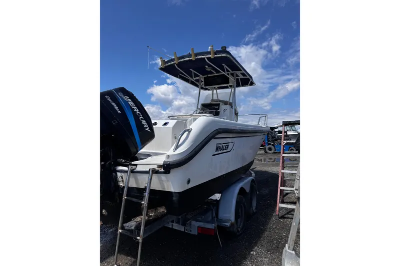 Slide: The Image of 2001 Boston Whaler 23 Outrage boat on trailer with Mercury engine, under blue sky. - 5