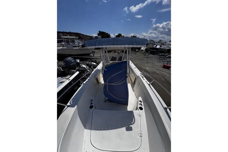 Slide: The Image of 2001 Boston Whaler 23 Outrage boat with blue canopy, docked under a clear sky. - 14