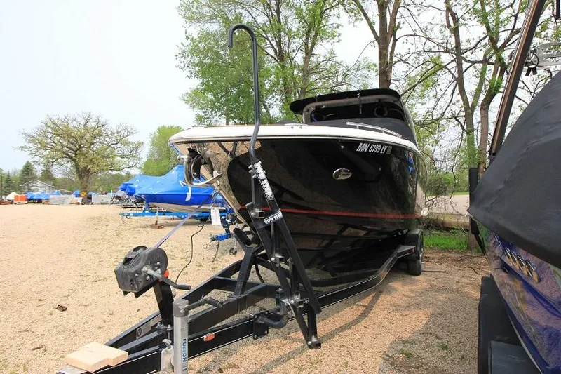 Slide: The Image of A black 2016 Regal 2800 Bowrider boat on a trailer in a gravel lot. - 2