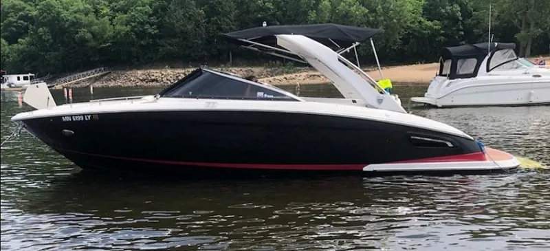 Slide: The Image of A black 2016 Regal 2800 Bowrider floats on calm water, surrounded by trees. - 31