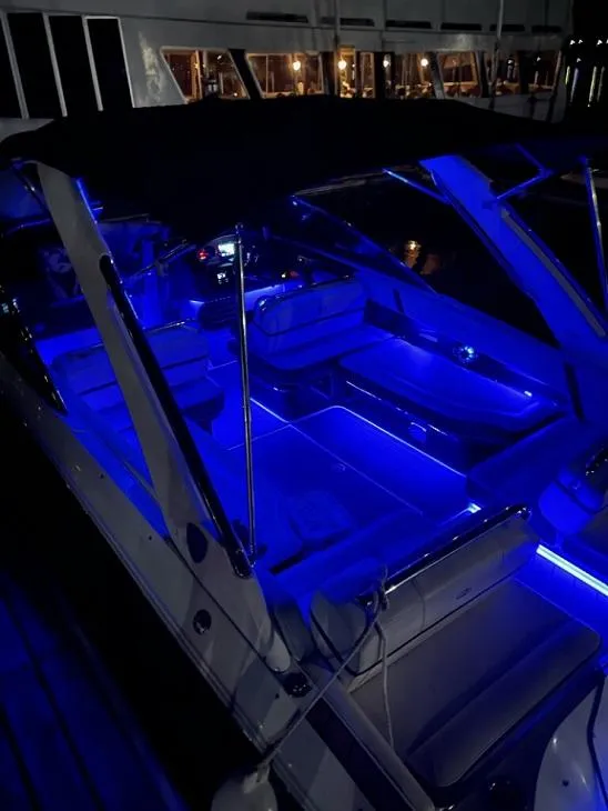 Slide: The Image of A 2016 Regal 2800 Bowrider with blue LED lighting in the cockpit area, docked at night. - 29