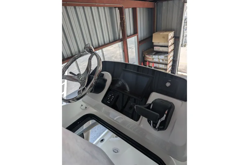 Slide: The Image of 2027 Tidewater 2410 Bay Max boat console with steering wheel and controls in storage. - 18