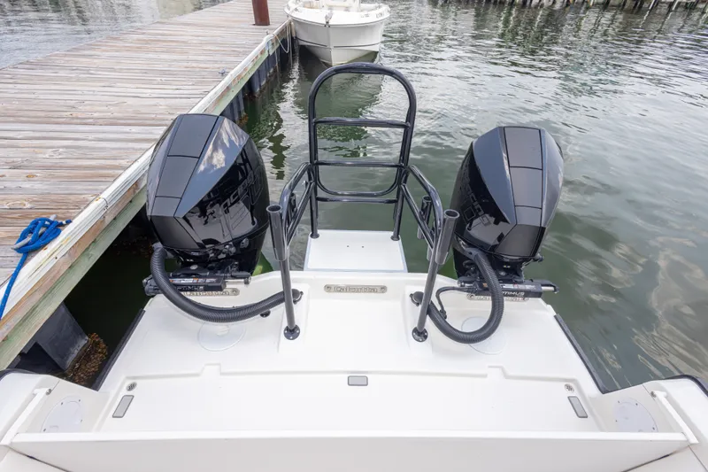 Slide: The Image of Twin outboard motors on a 2026 Calcutta 263 boat docked by the water. - 68