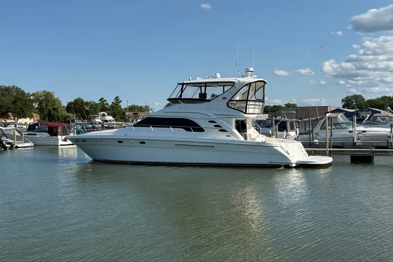 The Image of 2002 Sea Ray 560 Sedan Bridge yacht docked in a marina under a clear blue sky. - 0