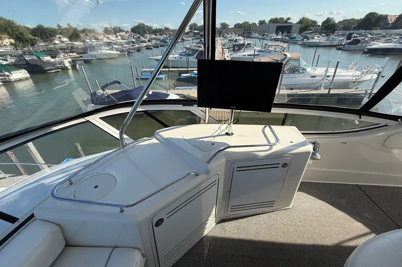 Slide: The Image of 2002 Sea Ray 560 Sedan Bridge helm with marina view, featuring a mounted screen and seating area. - 26