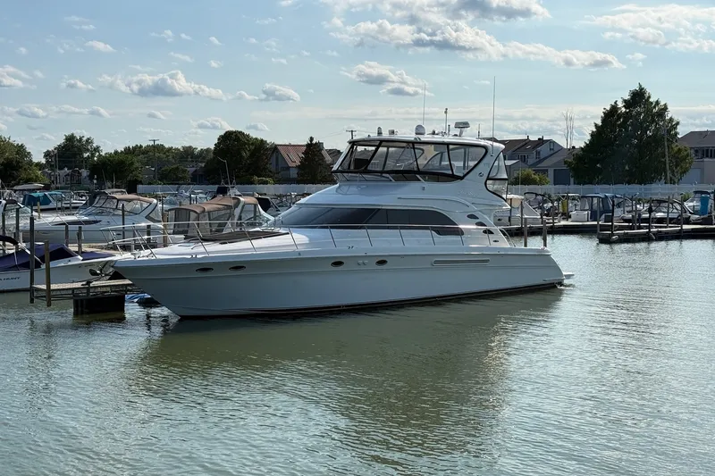 Slide: The Image of 2002 Sea Ray 560 Sedan Bridge yacht docked in a marina under a partly cloudy sky. - 2