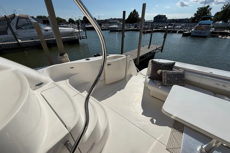Slide: The Image of 2002 Sea Ray 560 Sedan Bridge yacht deck with seating, table, and marina view. - 49