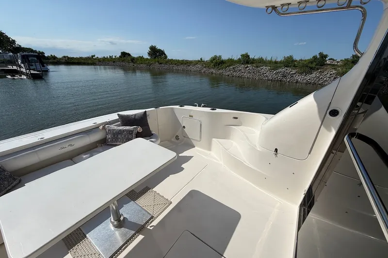 Slide: The Image of 2002 Sea Ray 560 Sedan Bridge yacht deck with seating and table, overlooking calm waters. - 15