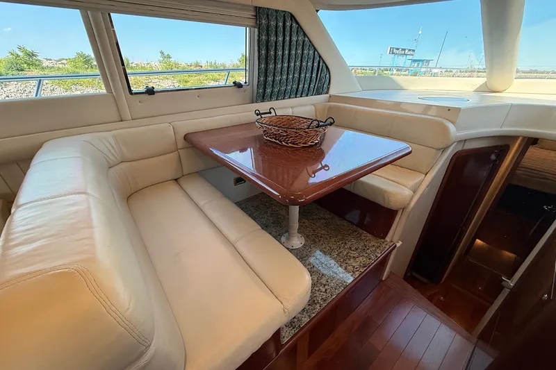 Slide: The Image of Luxurious interior of 2002 Sea Ray 560 Sedan Bridge with leather seating and wooden table. - 64