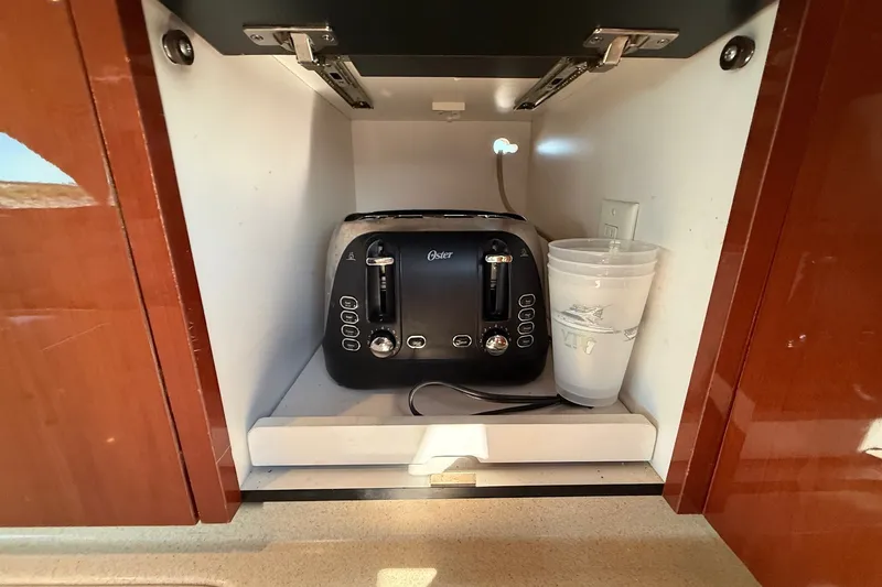 Slide: The Image of Cabinet interior with toaster and cups on a 2002 Sea Ray 560 Sedan Bridge yacht. - 69