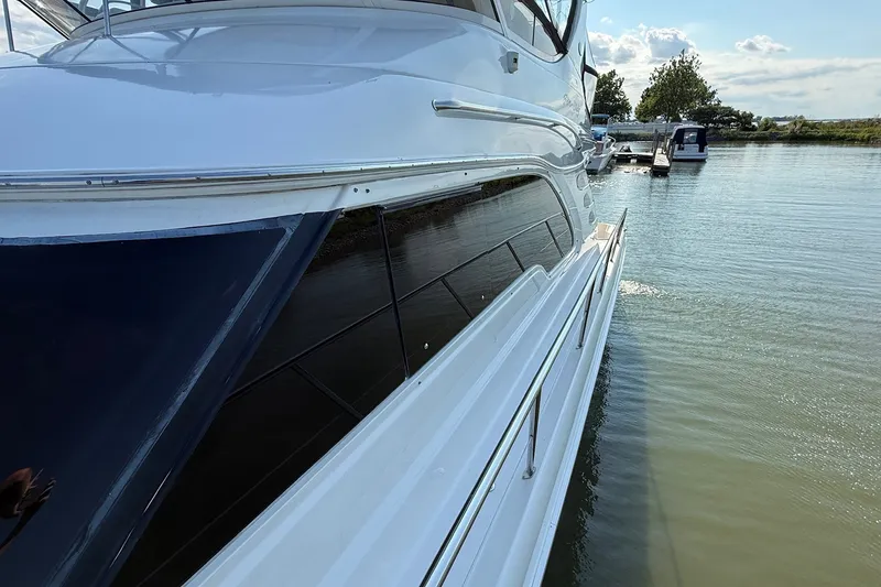 Slide: The Image of 2002 Sea Ray 560 Sedan Bridge yacht docked on calm water, side view. - 9