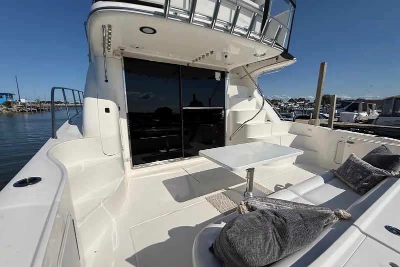Slide: The Image of 2002 Sea Ray 560 Sedan Bridge yacht deck with seating and table, docked at marina. - 11