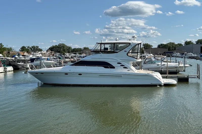 Slide: The Image of 2002 Sea Ray 560 Sedan Bridge yacht docked in a marina under a blue sky. - 1