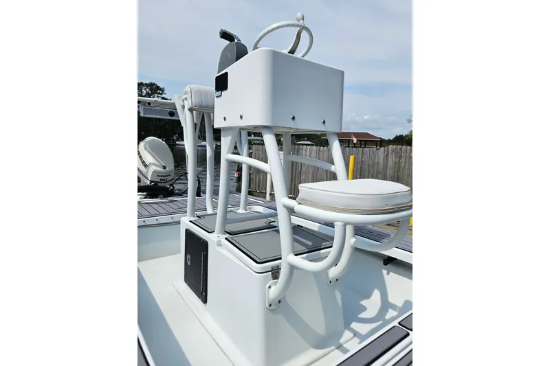 Slide: The Image of 2012 East Cape Fury boat helm with cushioned seat and steering wheel, docked outdoors. - 15