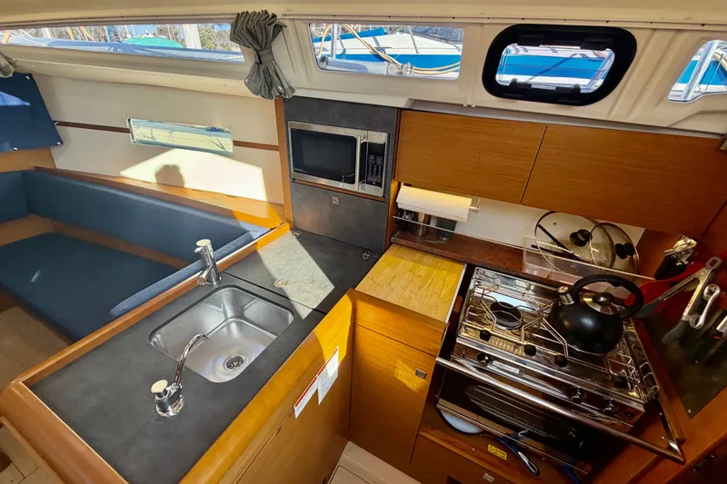 Slide: The Image of Interior of 2019 Jeanneau Sun Odyssey 349 yacht kitchen with sink, stove, and seating area. - 27