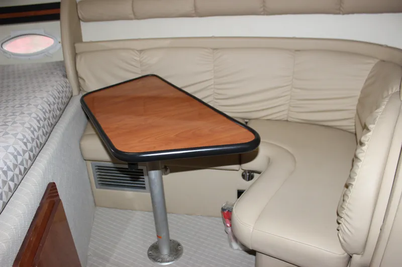 Slide: The Image of 2006 Rinker 290 Express Cruiser interior with beige seating and wooden table. - 23