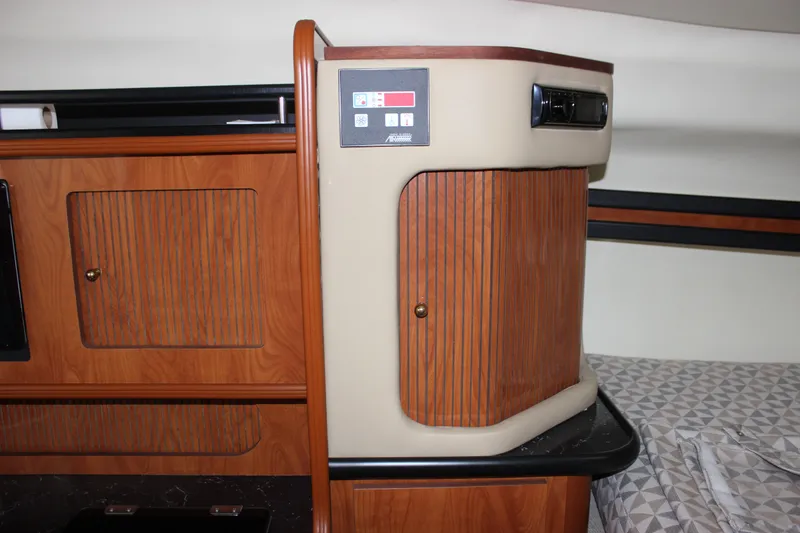 Slide: The Image of Interior of a 2006 Rinker 290 Express Cruiser with wooden cabinetry and control panel. - 27
