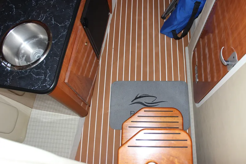 Slide: The Image of 2006 Rinker 290 Express Cruiser interior with sink, wooden cabinetry, and striped flooring. - 16