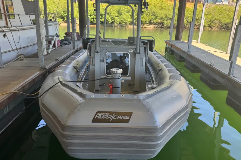 Slide: The Image of 2004 Zodiac Milpro Hurricane boat docked in a marina, surrounded by calm water. - 7