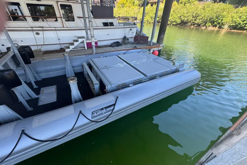 Slide: The Image of 2004 Zodiac Milpro Hurricane boat docked on calm water, featuring storage compartments. - 6