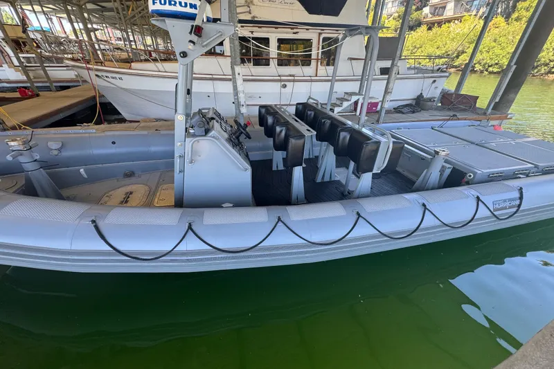 Slide: The Image of 2004 Zodiac Milpro Hurricane boat docked, featuring seating and control console. - 2