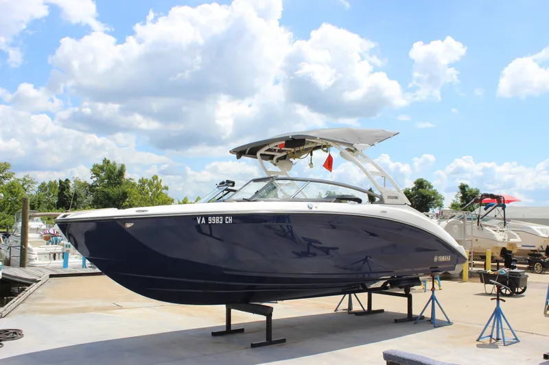 The Image of 2022 Yamaha Boats 252XE on display at a marina under a bright blue sky. - 0