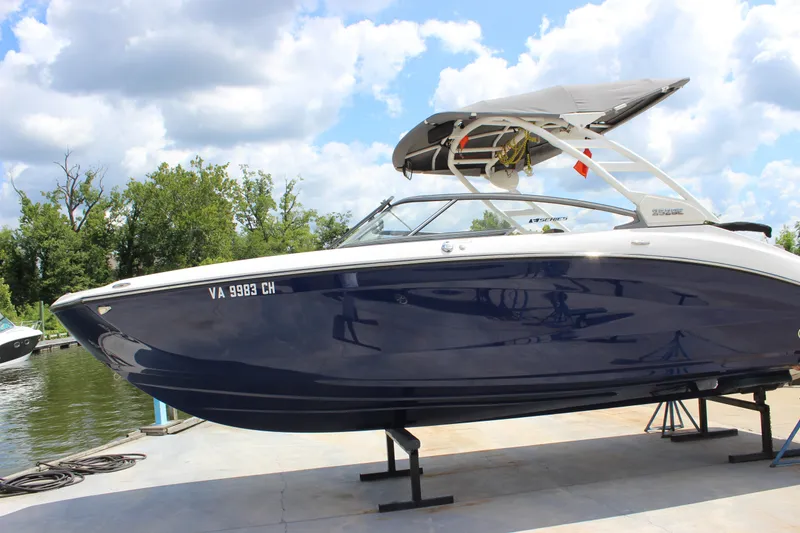 Slide: The Image of 2022 Yamaha Boats 252XE in blue, docked on a sunny day with trees in the background. - 24