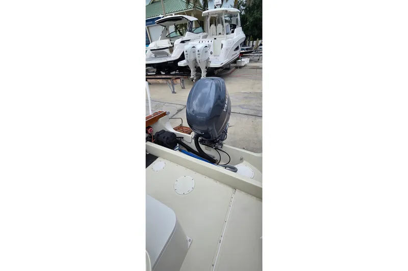 Slide: The Image of 1986 Boston Whaler Outrage 20 with outboard motor, docked near other boats. - 21
