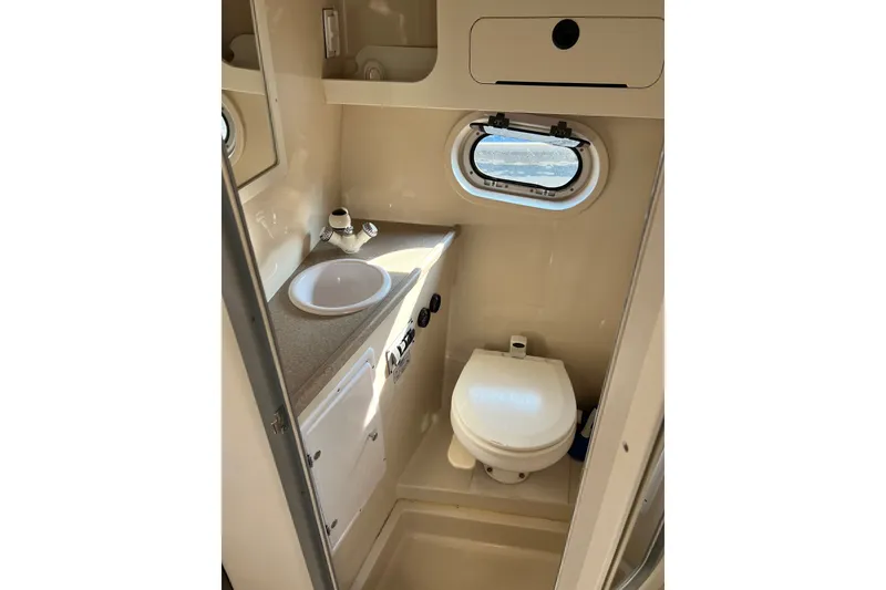Slide: The Image of Compact bathroom in 2003 Four Winns 298 Vista boat with sink, toilet, and porthole window. - 25