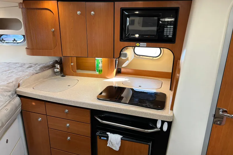 Slide: The Image of 2003 Four Winns 298 Vista boat interior kitchen with microwave, stove, and wooden cabinets. - 21