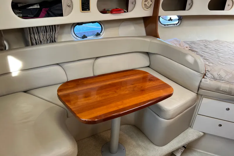 Slide: The Image of 2003 Four Winns 298 Vista cabin interior with wooden table and beige seating. - 19
