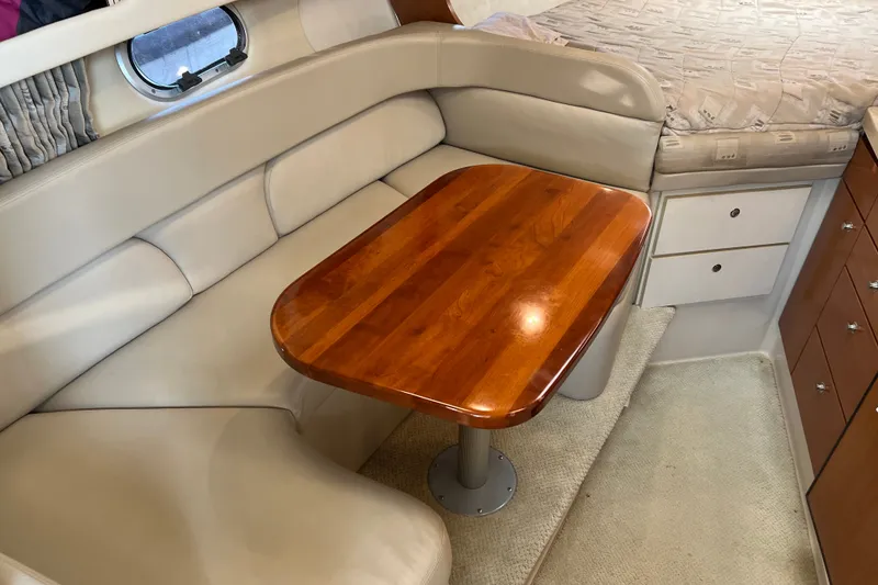 Slide: The Image of Interior of 2003 Four Winns 298 Vista boat with wooden table and beige seating. - 18