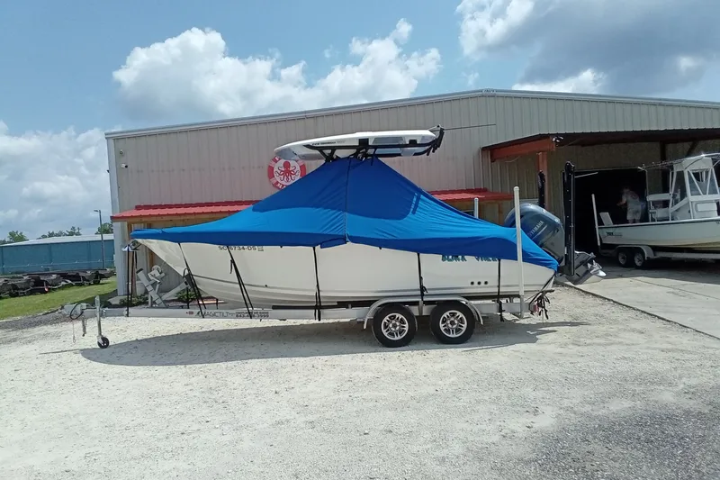 Slide: The Image of 2022 Sea Fox 228 Commander boat with blue cover on trailer, parked outside a warehouse. - 45