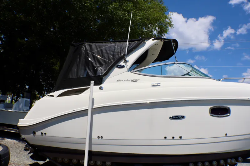 Slide: The Image of 2010 Sea Ray Sundancer 260 boat with canopy, parked outdoors under blue sky. - 60