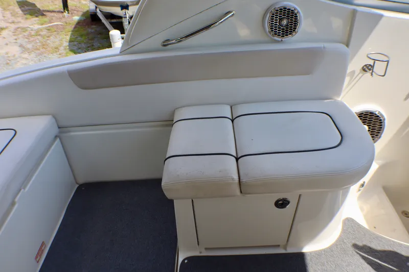 Slide: The Image of 2010 Sea Ray Sundancer 260 interior seating with white upholstery and built-in speakers. - 29