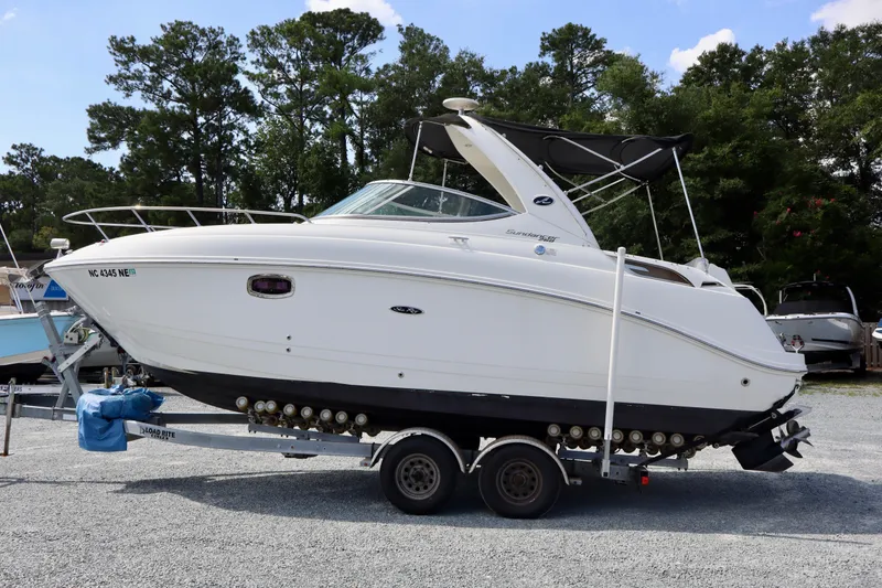 Slide: The Image of 2010 Sea Ray Sundancer 260 boat on trailer, parked outdoors with trees in background. - 4