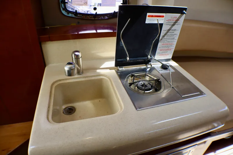 Slide: The Image of Compact kitchen area in a 2010 Sea Ray Sundancer 260 boat, featuring a sink and stove. - 40