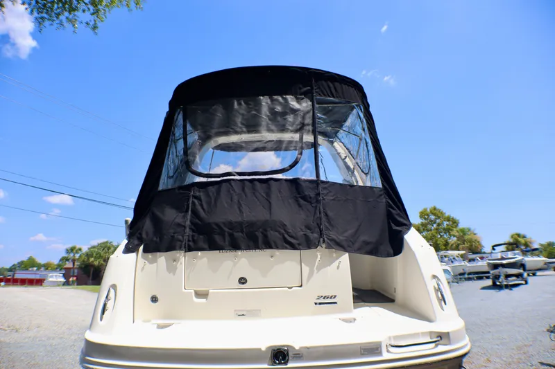 Slide: The Image of 2010 Sea Ray Sundancer 260 with black canvas cover, rear view under clear blue sky. - 59