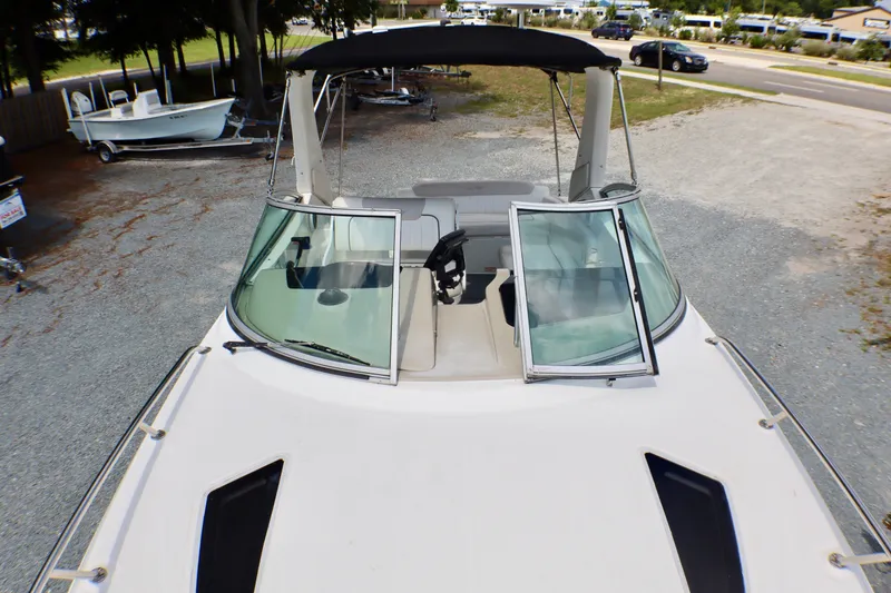 Slide: The Image of 2010 Sea Ray Sundancer 260 boat with open windshield, parked on gravel. - 19