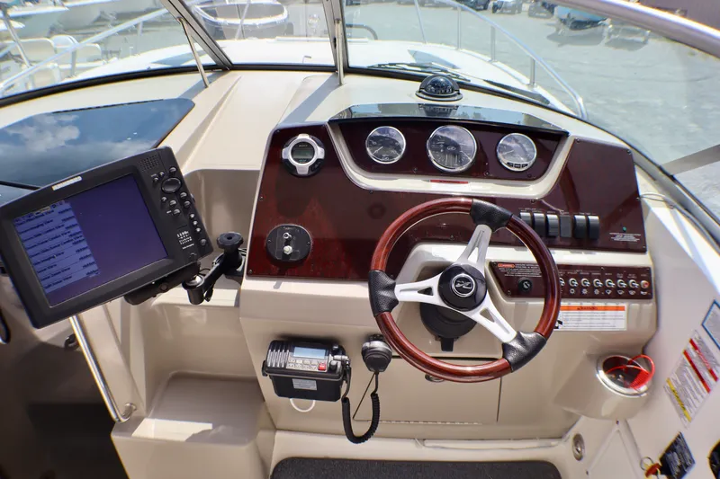 Slide: The Image of Cockpit of 2010 Sea Ray Sundancer 260 with steering wheel and navigation controls. - 14