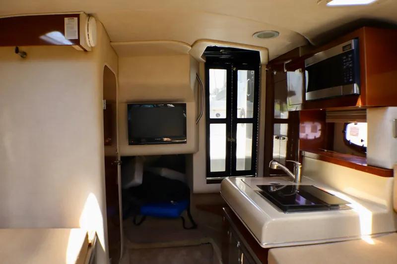 Slide: The Image of Interior of 2010 Sea Ray Sundancer 260, featuring kitchenette, TV, and modern amenities. - 48
