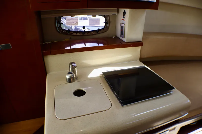 Slide: The Image of Interior of 2010 Sea Ray Sundancer 260, featuring a compact kitchenette with sink and stove. - 38