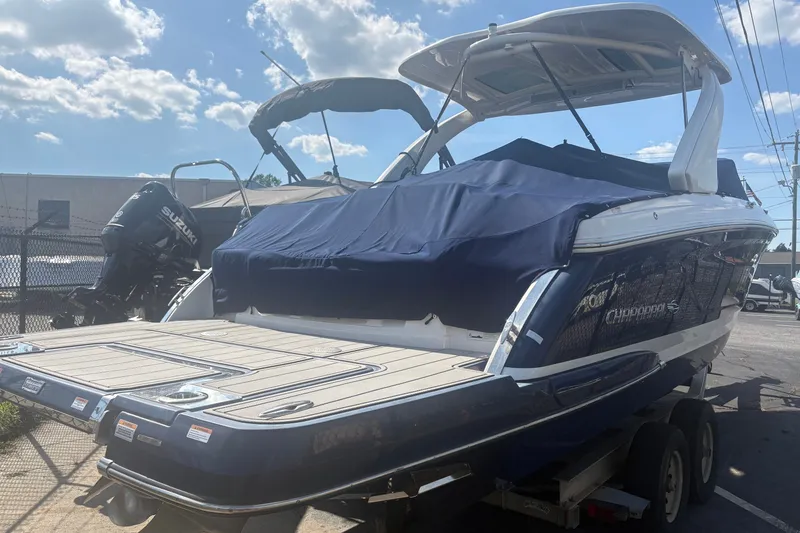 Slide: The Image of 2022 Chaparral 307 SSX boat with covered deck, parked on a trailer under a sunny sky. - 1