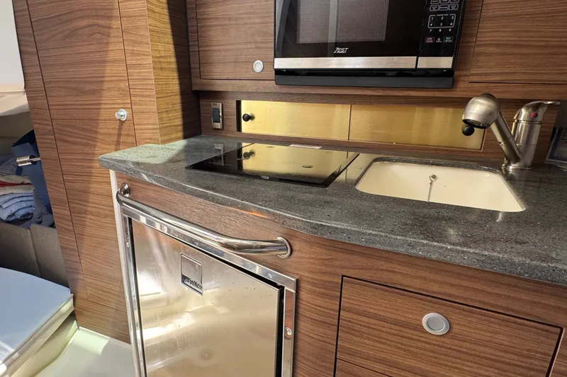 Slide: The Image of 2023 Boston Whaler 325 Conquest kitchen with microwave, sink, and stove. - 27