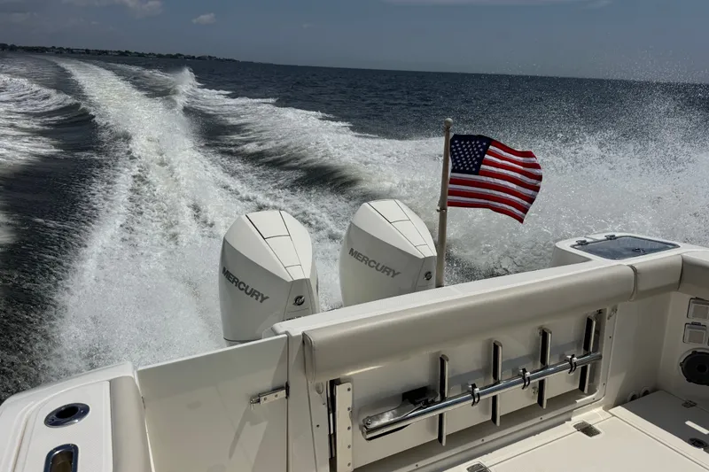 Slide: The Image of 2023 Boston Whaler 325 Conquest cruising with American flag and twin Mercury engines. - 9